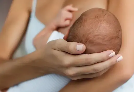 Młoda kobieta karmiąca piersią swoje nowo narodzone dziecko w domu